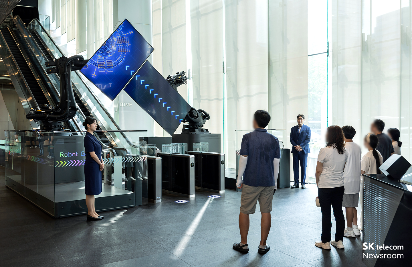 로봇 게이트 앞에서 투어 시작 전에 T.um에 관한 소개를 받고 있는 고객들