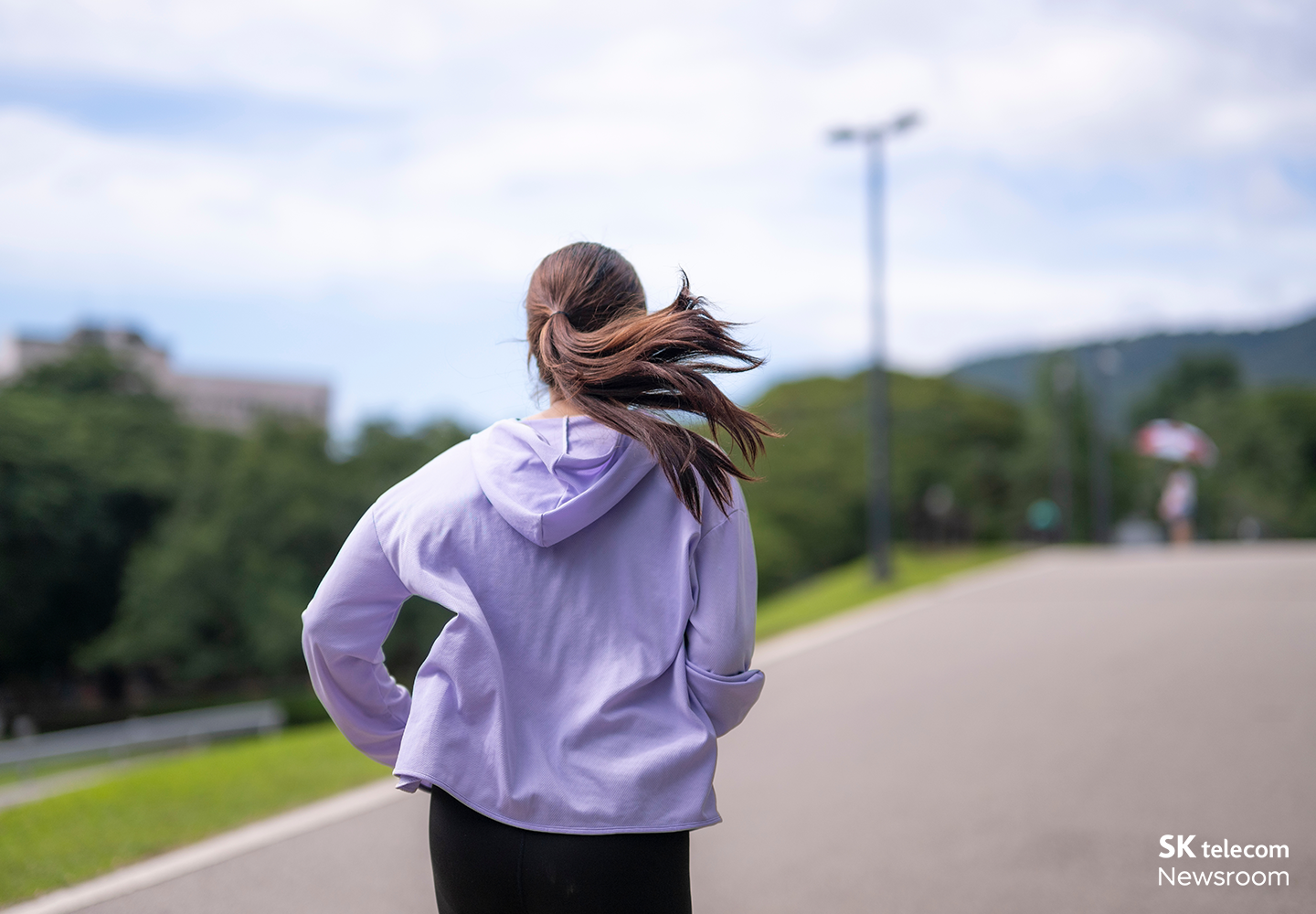 야외 도로에서 러닝복 차림의 여성이 달리는 뒷모습.