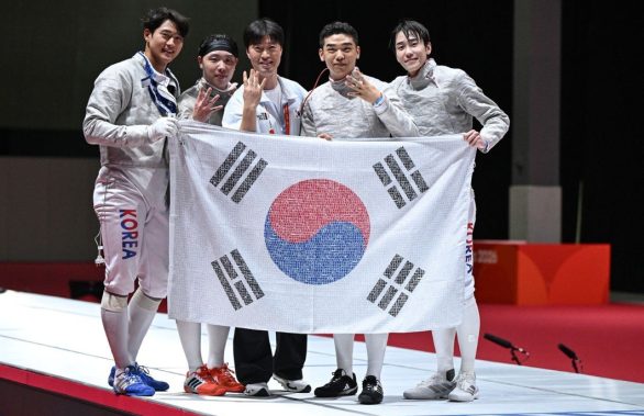 2026 아이치·나고야 아시안게임 펜싱 남자 사브르 단체전에서 4연패를 달성한 대한민국 대표팀 선수단이 국민 응원 메시지가 담긴 태극기를 들고 기념 촬영을 하고 있다.
